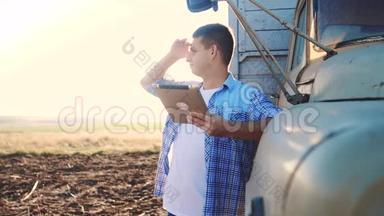 聪明的农业司机。 男子农民司机站在卡车附近的数字平板电脑。 慢动作视频。 肖像